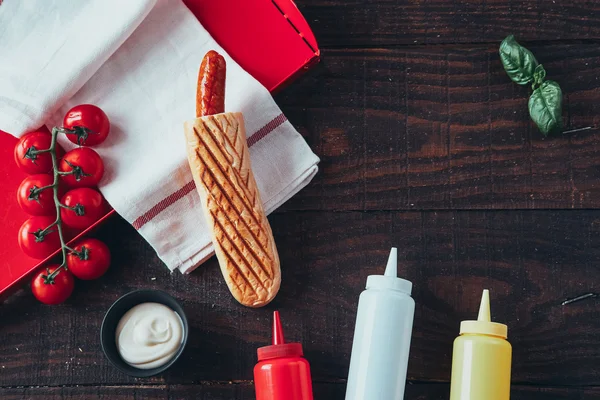 Hot dog con mostaza, ketchup y mayonesa sobre fondo de madera. Vista superior — Foto de Stock