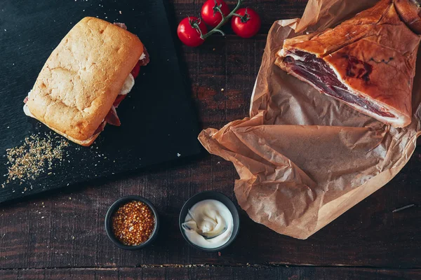 Vaření chutné panini s šunkou pokryté sýrem, rajčaty a příchuti — Stock fotografie