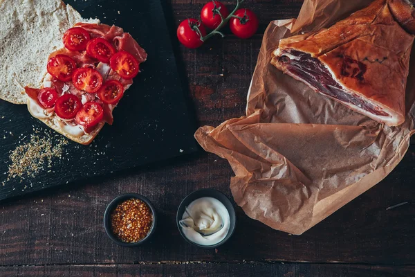 Vaření chutné panini s šunkou pokryté sýrem, rajčaty a příchuti — Stock fotografie