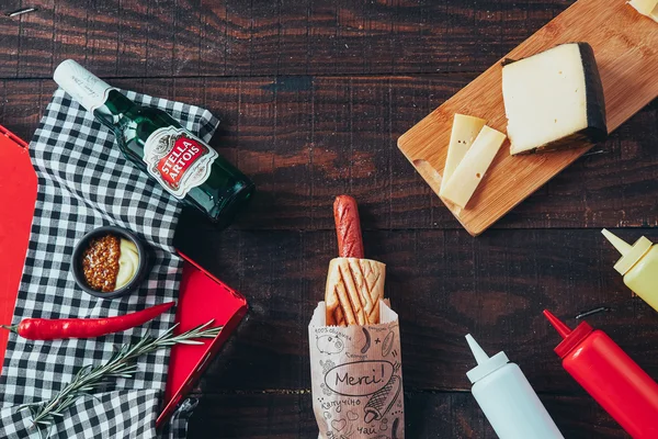 Hot dog con mostaza, ketchup y mayonesa sobre fondo de madera. Vista superior — Foto de Stock