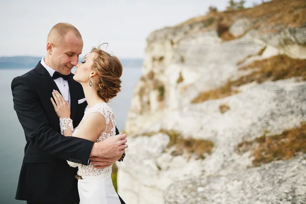 Amantes de la sesión de fotos en un vestido de novia en las montañas cerca de la s —  Fotos de Stock