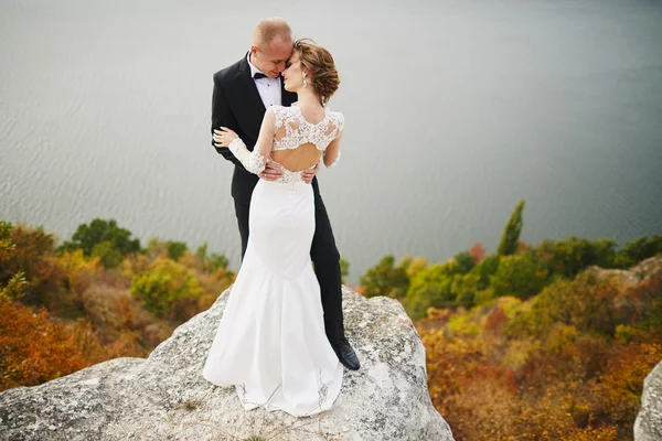 Amantes de la sesión de fotos en un vestido de novia en las montañas cerca de la s —  Fotos de Stock