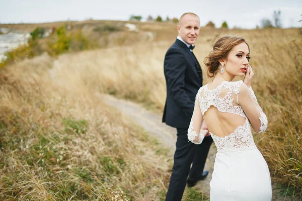 Fotocaça amantes em um vestido de noiva nas montanhas perto do s — Fotografia de Stock