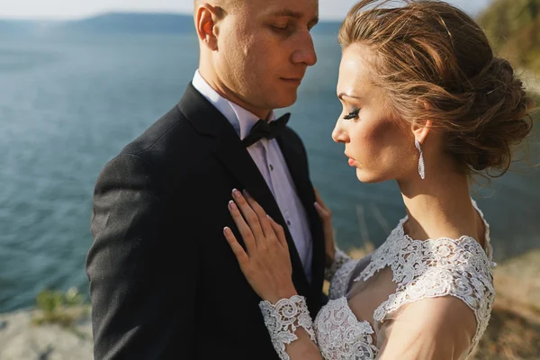 Amantes de la sesión de fotos en un vestido de novia en las montañas cerca de la s — Foto de Stock