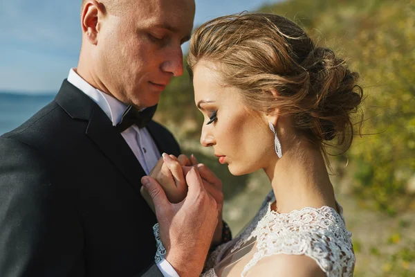 Amantes de la sesión de fotos en un vestido de novia en las montañas cerca de la s —  Fotos de Stock