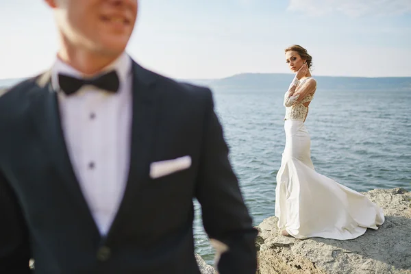 Amantes de la sesión de fotos en un vestido de novia en las montañas cerca de la s —  Fotos de Stock