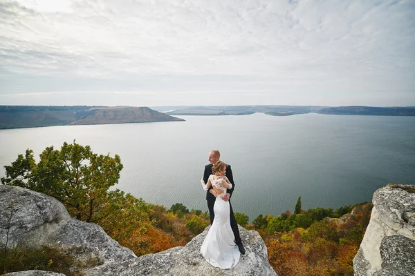 Amantes de la sesión de fotos en un vestido de novia en las montañas cerca de la s —  Fotos de Stock