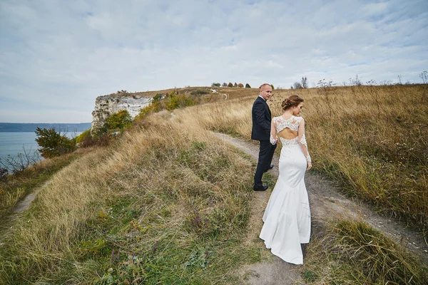 Коханці фотосесії в весільній сукні в горах біля с — стокове фото