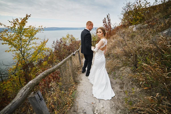 Focení milenců ve svatebních šatech v horách poblíž s — Stock fotografie