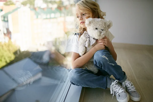 Молодая красивая девушка в джинсах одежда у окна с медведем — стоковое фото