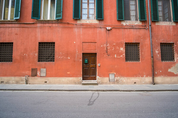 Red Building with Green Windows on the street in the city of Pisa, Italy.