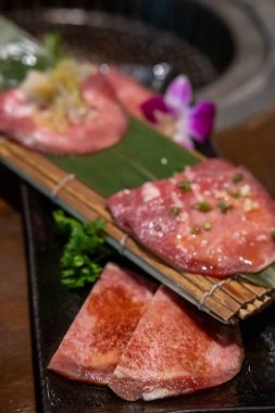 Japon usulü dilimlenmiş az pişmiş et tabakta, yumuşak odaklı.