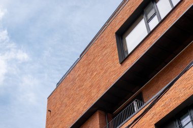 Arka planda mavi gökyüzü olan modern bir tuğla bina.