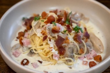 Jambon ve pastırmalı spagetti beyaz tabakta servis ediliyor. Yumuşak Odaklanma.