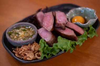 Yumurta sarısı ve sosla servis edilen ızgara sığır dili.