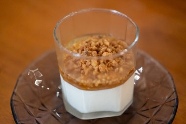 Panna Cotta cam bardakta, restoranda masanın üstünde.