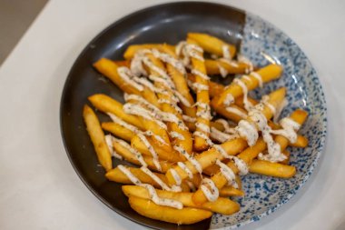 Peynirli patates kızartması ve tabakta siyah mantar sosu.