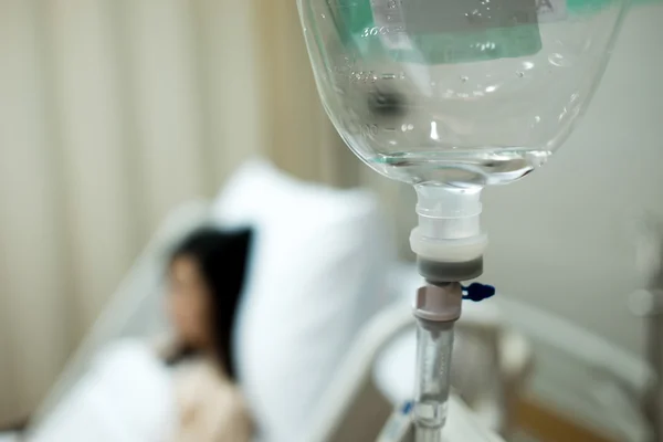 Saline IV drip bottle provided to the patient girl on the background — Stock Photo, Image