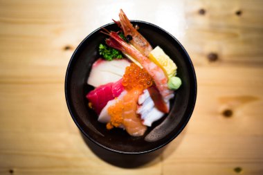 Chirashi suşi, Japon yemekleri pirinç kase Çiğ somon balığı, karışık deniz ürünleri, üstten görünüm, darken kenar, ortaya hizalı kopya alanı üzerinde ahşap masa, somon yumurta ile alan efekti derinliğini odaklanmak ile