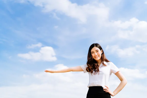 Bella giovane asiatica universitaria o studentessa universitaria fare pubblicità o presentare il prodotto posa, copiare spazio su sfondo cielo blu, istruzione o lavoro o concetto di pubblicità — Foto Stock