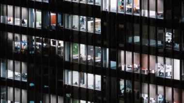 Gece geç saatlere kadar çalışan insanların süreleri, ofis pencereleri iş merkezinin ön cephesine bakıyor. Şirket işi, ofis işçisi hayatı ya da dış mimari konsepti. Eğil.