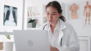 Asyalı kadın doktor bilgisayarlı bilgisayarla uzaktan kumandayla hastayla konuşuyor, reçete yazıyor. Tele sağlık, tele sağlık, hastane kliniği sağlık hizmetleri, veya internet teknolojisi konsepti