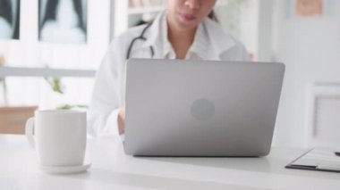 Asyalı kadın doktor bilgisayarlı bilgisayarla uzaktan kumandayla hastayla konuşuyor, reçete yazıyor. Tele sağlık, tele sağlık, hastane kliniği sağlık hizmetleri, veya internet teknolojisi konsepti