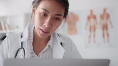 Asyalı kadın doktor bilgisayarlı bilgisayarla uzaktan kumandayla hastayla konuşuyor, reçete yazıyor. Tele sağlık, tele sağlık, hastane kliniği sağlık hizmetleri, veya internet teknolojisi konsepti