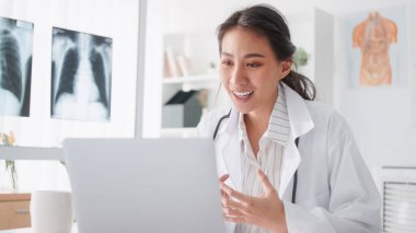 Asyalı kadın doktor bilgisayarlı bilgisayarla uzaktan kumandayla hastayla konuşuyor, reçete yazıyor. Tele sağlık, tele sağlık, hastane kliniği sağlık hizmetleri, veya internet teknolojisi konsepti