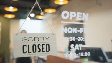 Asyalı bayan restoran sahibi yüz maskesi takıyor, dükkanın tabelasını Kapalı 'dan Açık' a çeviriyor. İş, covid-19 koronavirüs salgınından, Covid rahatlamasından ya da yeni normal yaşam tarzı kavramından sonra yeniden açıldı.
