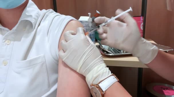 アジアの男性はフェイスマスクを着用し 病院や医療機関で看護師や一般開業医によってコロナウイルスワクチン注射ジャブを受け取ります 予防接種やコヴィト19のパンデミック救済の概念についての人々 — ストック動画