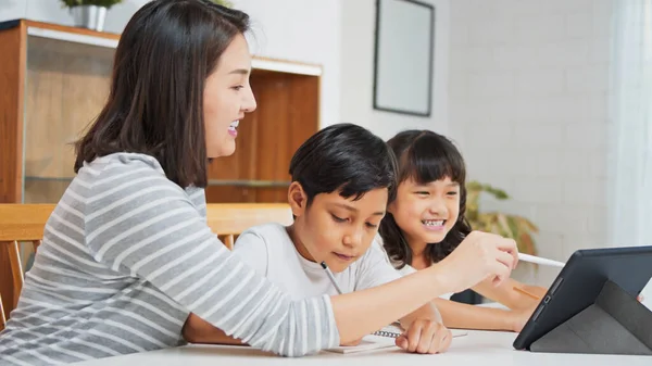 Azjatycka Matka Uczy Młodego Syna Córkę Pracy Domowej Używając Tabletu — Zdjęcie stockowe