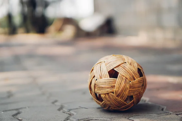 Sepak Takraw bola en ladrillos de baldosas de pavimento con espacio de copia, fondo borroso. Sudeste Asiático famoso deporte local o concepto de actividades asiáticas —  Fotos de Stock