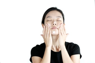 Cute asian girl applying cream lotion on face, isolated on white background