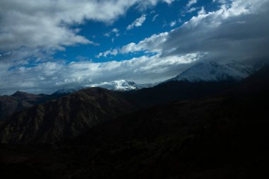 Şili 'deki And Dağları' nın tepesinin bir kısmını aydınlatmak için bulutlu gökyüzünü geçen ürkek güneş ışınları.