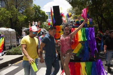 Mexico City, MEXICO - 29 Mayıs 2019: Transeksüel hayranını gökkuşağı renkleriyle süslenmiş bir şamandıranın yanında pullu bir takım elbise ve çorapla yetiştirirken,
