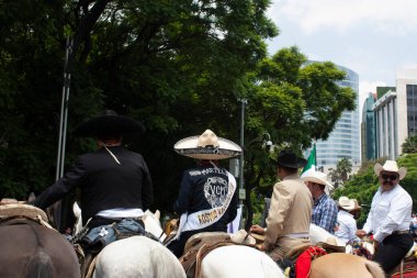 Mexico City, MEXICO - 29 Mayıs 2019: Mariachis, Mexico City 'deki LGBTTI yürüyüşünü canlandırmak için atlarına bindi ve Avenida de la Reforma' da gösteri yapan insanlar arasında şapka taktı.