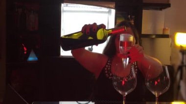 Kırmızı şarap servisi yapan kadın içki içmek için havalandırma aleti ve bar tezgahında balon bardakları kullanıyor.