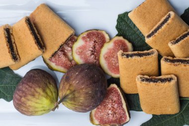 İncir çubuğu, iki taze incir ve beyaz servis tabağında incir yapraklı dilimlenmiş incir. Yüksek kalite fotoğraf