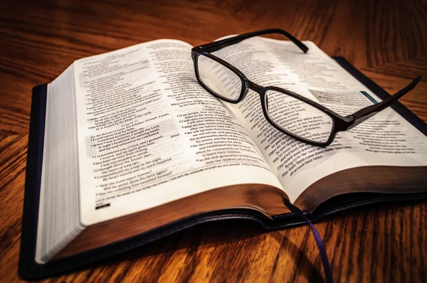 안경을 끼고 탁자 위에서 성서 연구 책을 펼쳐 놓으라 스톡 사진