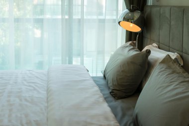 metal masa lambası ve yatakta gri yastık