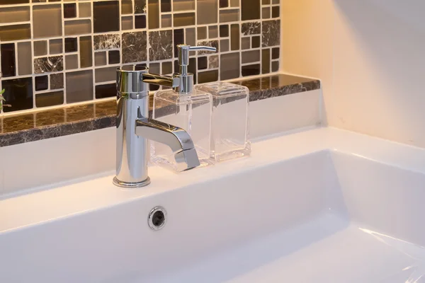 Lavabo con grifo y botella de jabón líquido en casa — Foto de Stock