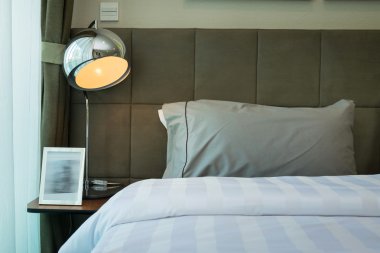 metal masa lambası ve yatakta gri yastık