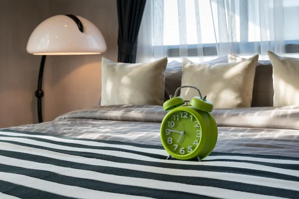 Dormitorio moderno con reloj despertador verde en la cama — Foto de Stock