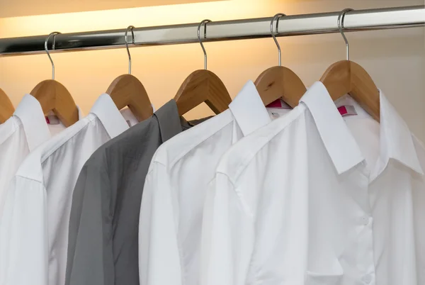 row of shirts hanging on coat hanger in white wardrobe