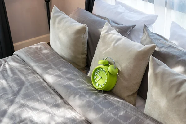 Dormitorio moderno con despertador verde y almohadas en la cama — Foto de Stock