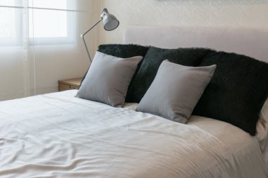 beyaz yatak ve dekoratif masa lambası gri yastık ile yatak odası iç tasarım.