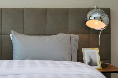 metal masa lambası ve yatakta gri yastık