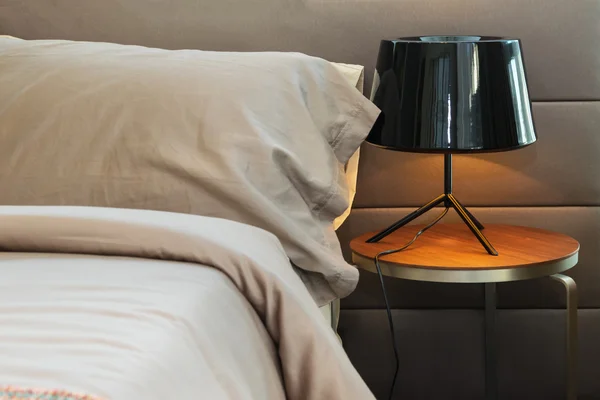 Moderne schwarze Lampe und braunes Kissen auf dem Bett — Stockfoto