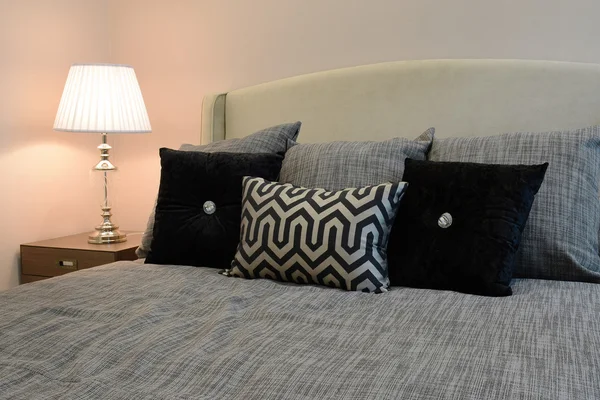 Sylish 卧室室内设计与黑色图案枕头在床上和装饰台灯. — 图库照片